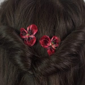 Close up of two Deep Red Pansy Flower Hair Clips in a twisted half up do