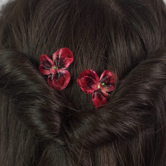 Close up of two Deep Red Pansy Flower Hair Clips in a twisted half up do