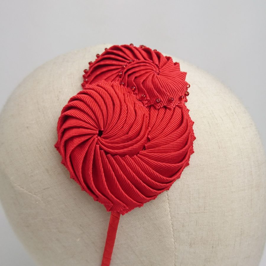 Close up of handmade nautilus shells, made from red ribbon. Hair accessories for a spring or summer wedding unique headband.