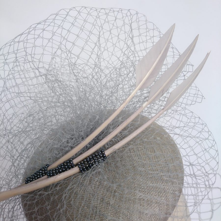 Detail of a grey hat with veiling feathers and beading