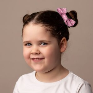 Dusky Pink Polka Dot Hair Clip worn by a child with a bun hair style