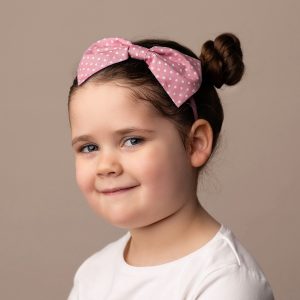 Dusky Pink Polka Dot Headband worn by a child with a bun hair style