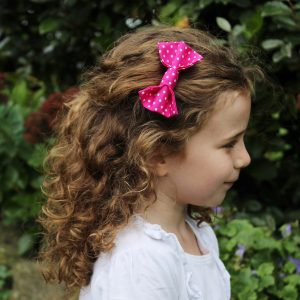 Hot Pink Polka Dot Hair Clip worn by a child with light brown curly hair