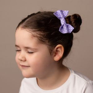 Lilac Polka Dot Hair Clip worn by a child with a bun hair style