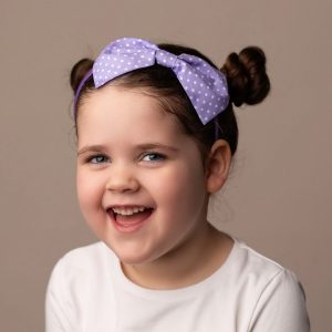 Lilac Polka Dot Headband worn by a child with a bun hair style