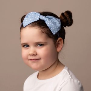 Pale Blue Polka Dot Headband worn by a child with a bun hair style