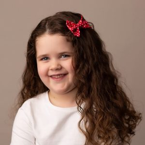 Red Polka Dot Hair Clip worn by a child with a long curly hair