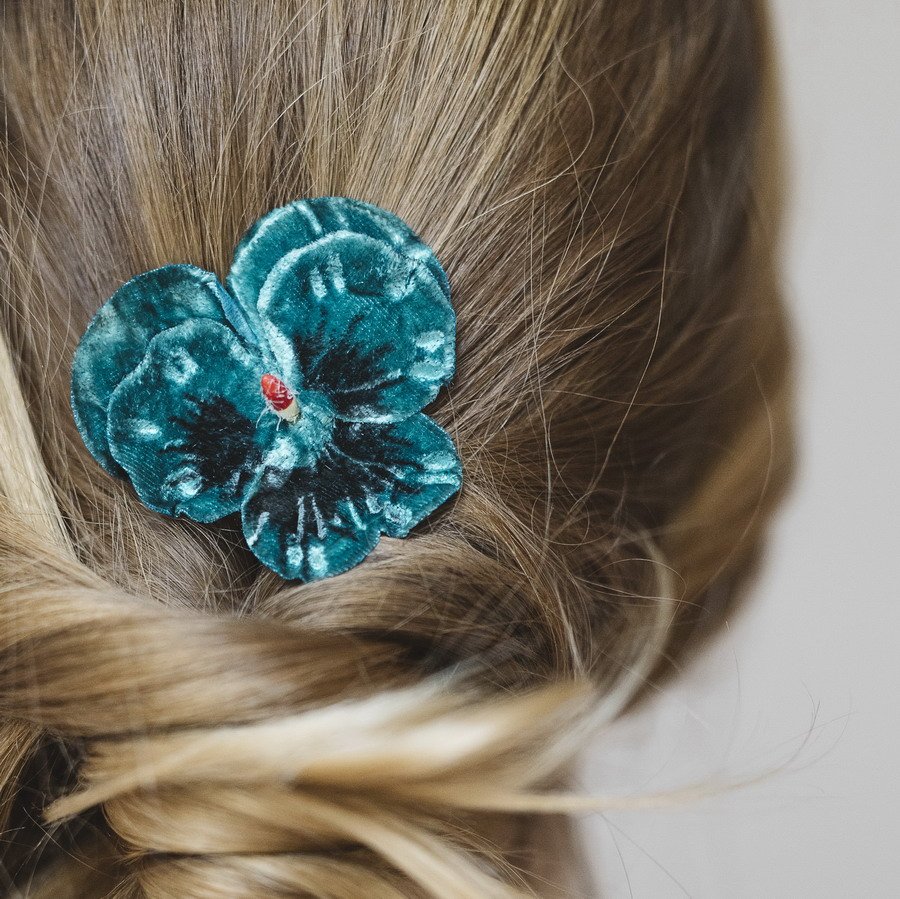 Detail image of Teal Pansy Flower Hair Clip worn with a ponytail