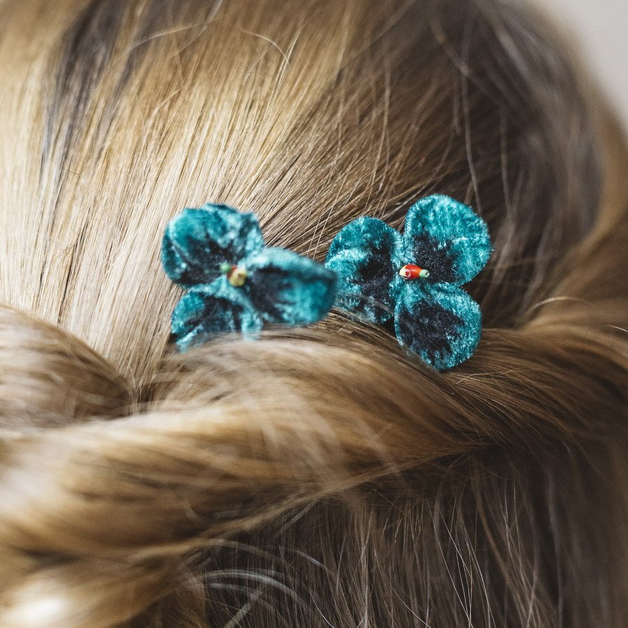Close up of blue/green velvet flowers in a twisted half-up-do