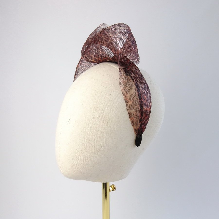 Leopard print vegan friendly knotted headband worn to the left of the head