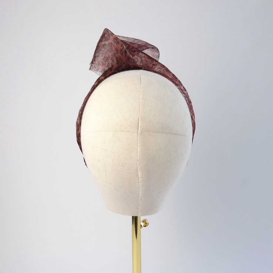 Back view of leopard print mesh knotted hair accessory worn to the left of the head