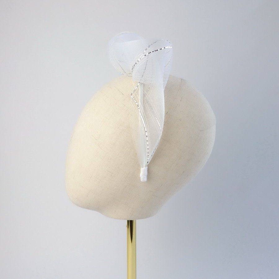 White and silver knotted bridal hair accessory worn to the left of the head