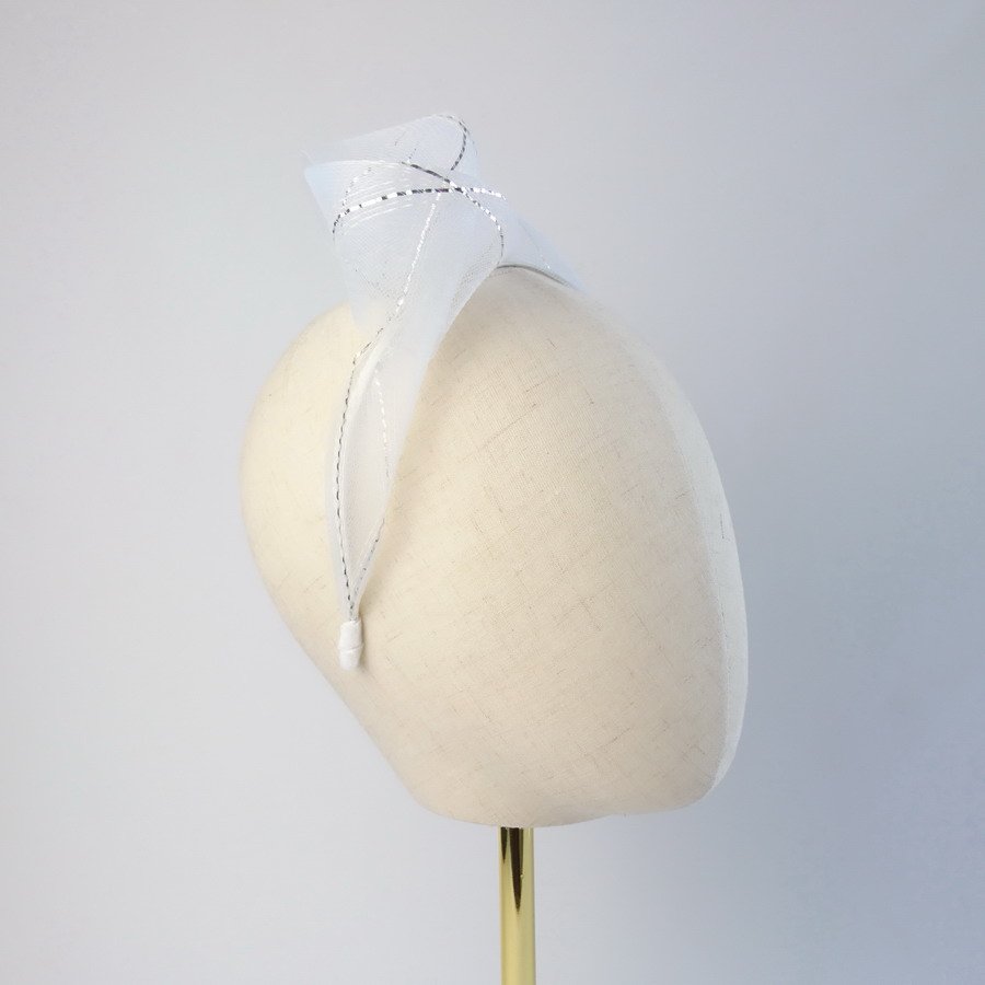 White and silver vegan friendly knotted headband worn to the right of the head
