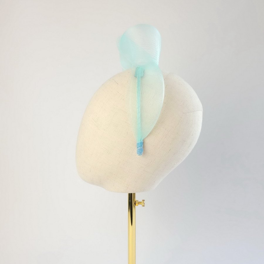 Aqua blue statement knot headband worn to the left of the head