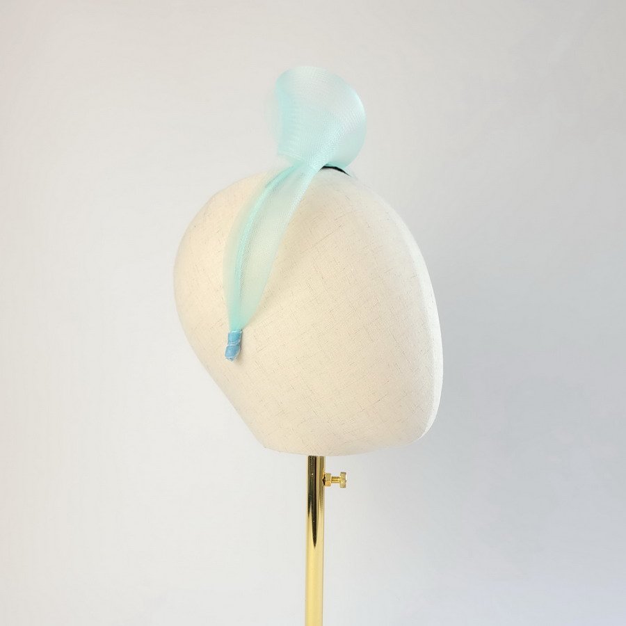 Aqua blue mesh knotted hair accessory worn to the right of the head