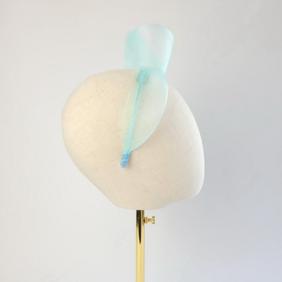 Aqua blue vegan friendly knotted headband worn to the right of the head