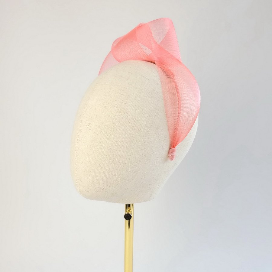Coral pink statement knot headband worn to the left of the head