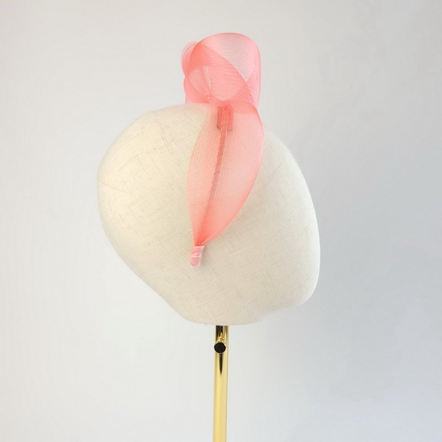 Coral pink mesh knotted hair accessory worn to the right of the head