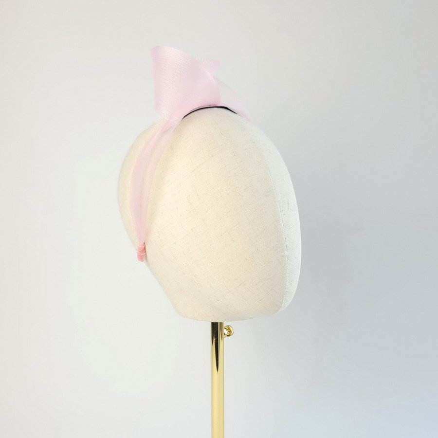 Pale pink statement knot headband worn to the right of the head
