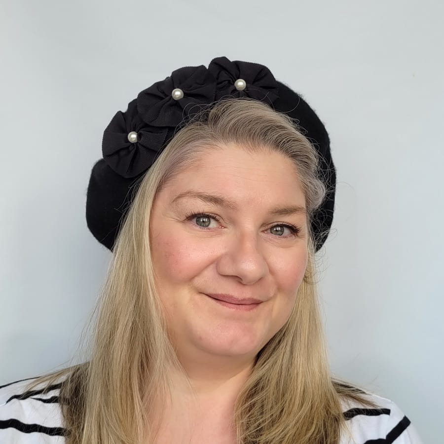 Black Beret with Ribbon Rosettes and Pearls worn by a white woman in her 40s with long blonde hair